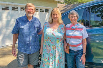 Three people standing outside smiling and posing for the picture
